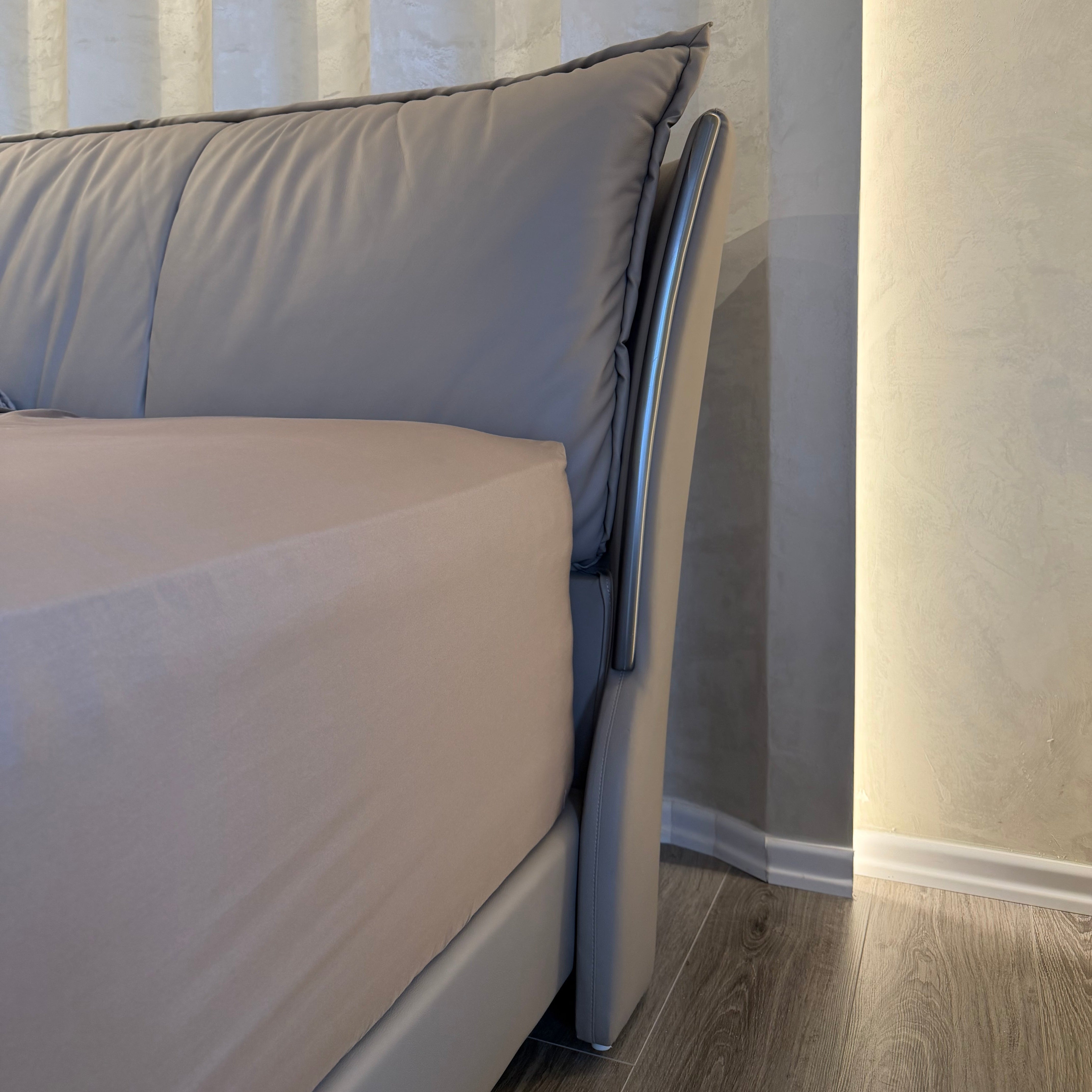 Gray cushioned bench against a neutral wall