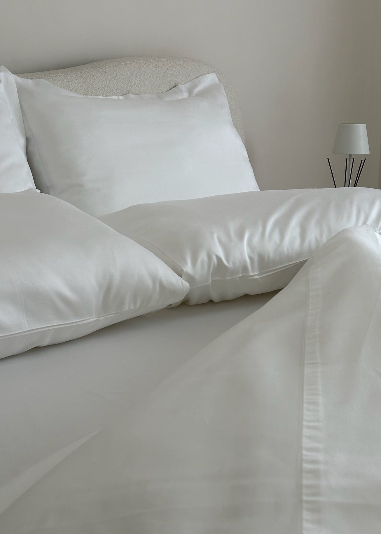 White bedding set on a bed with a neutral wall background