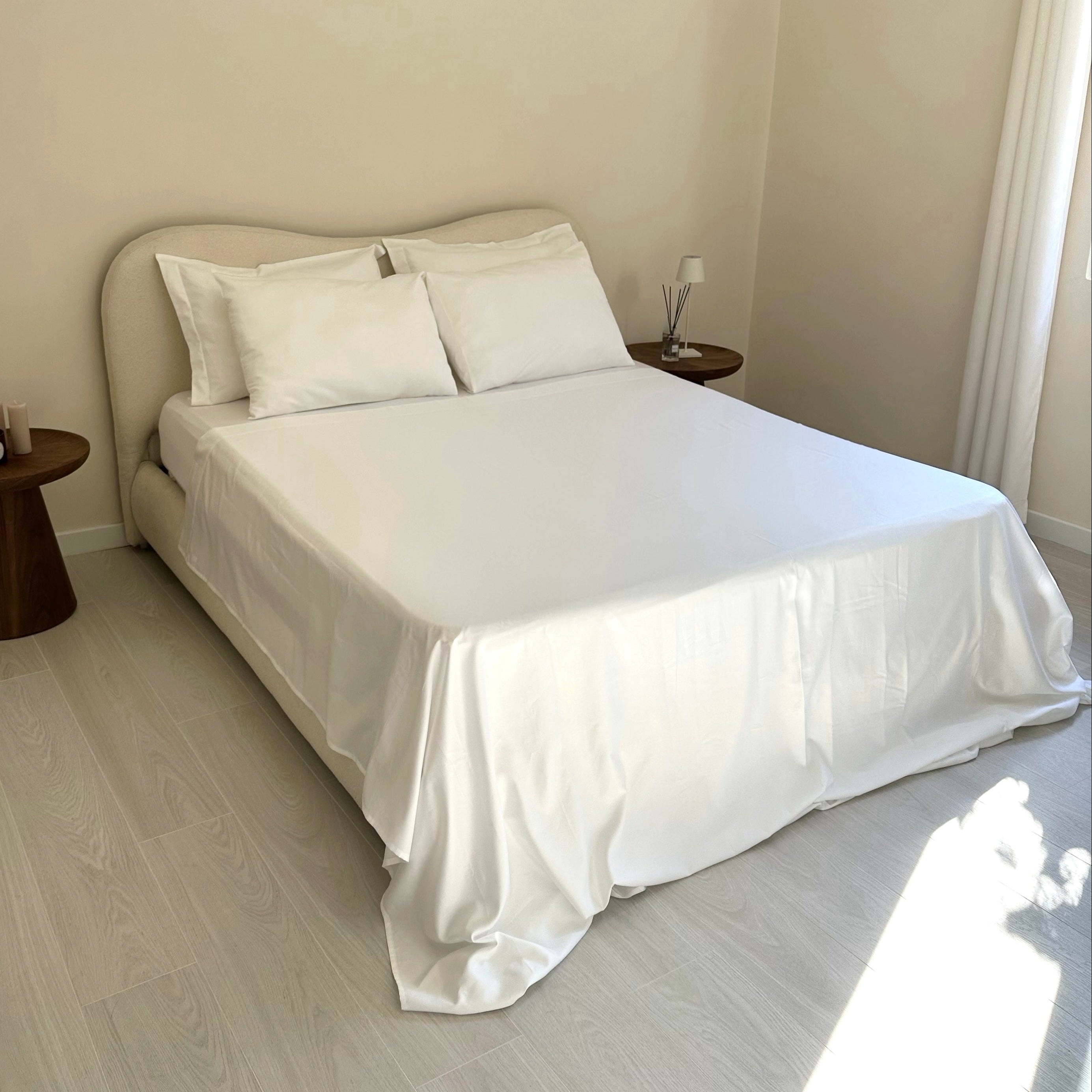 Neatly made bed with white bedding in a minimalistic bedroom.