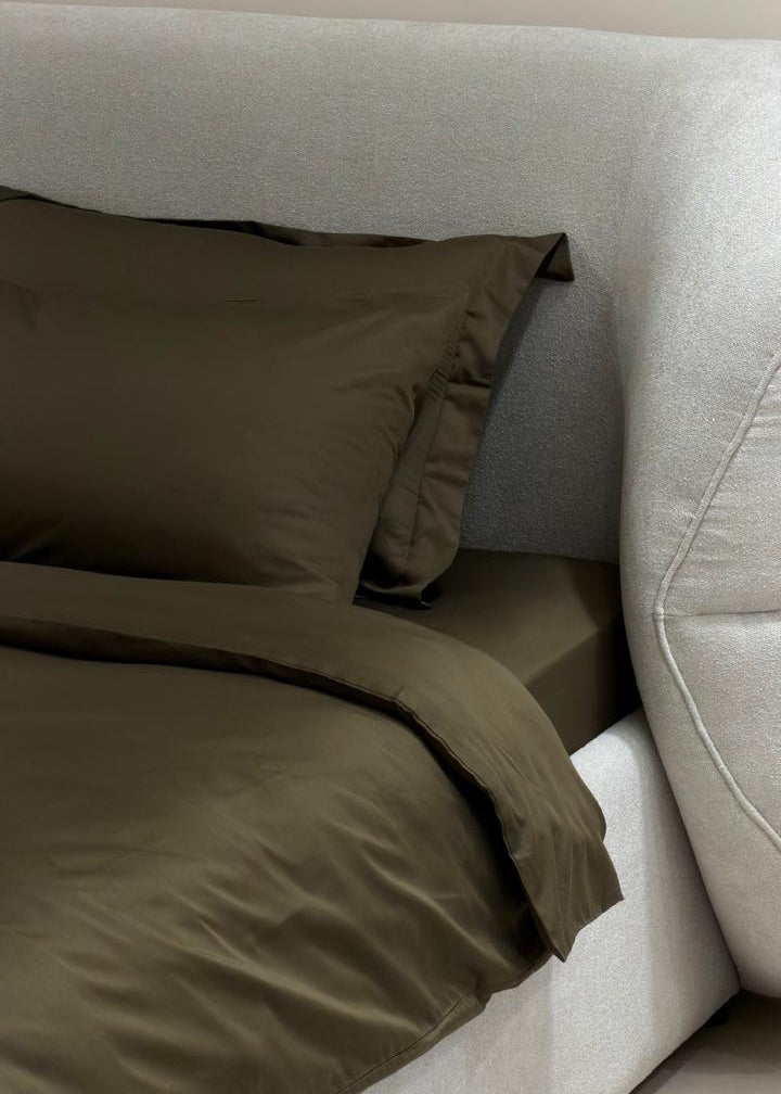 Brown bedding on a bed with a neutral headboard