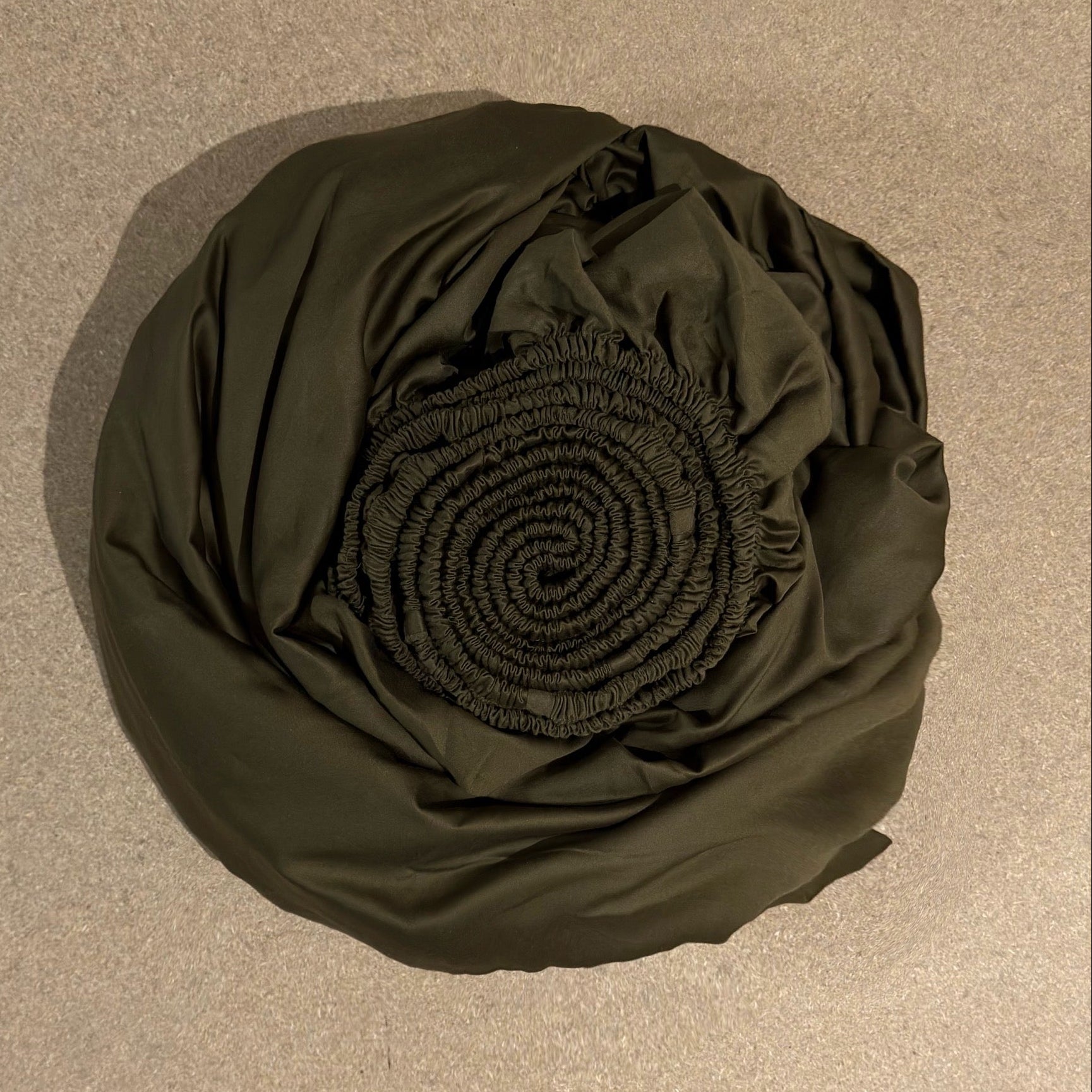 Rolled-up black fabric on a beige surface