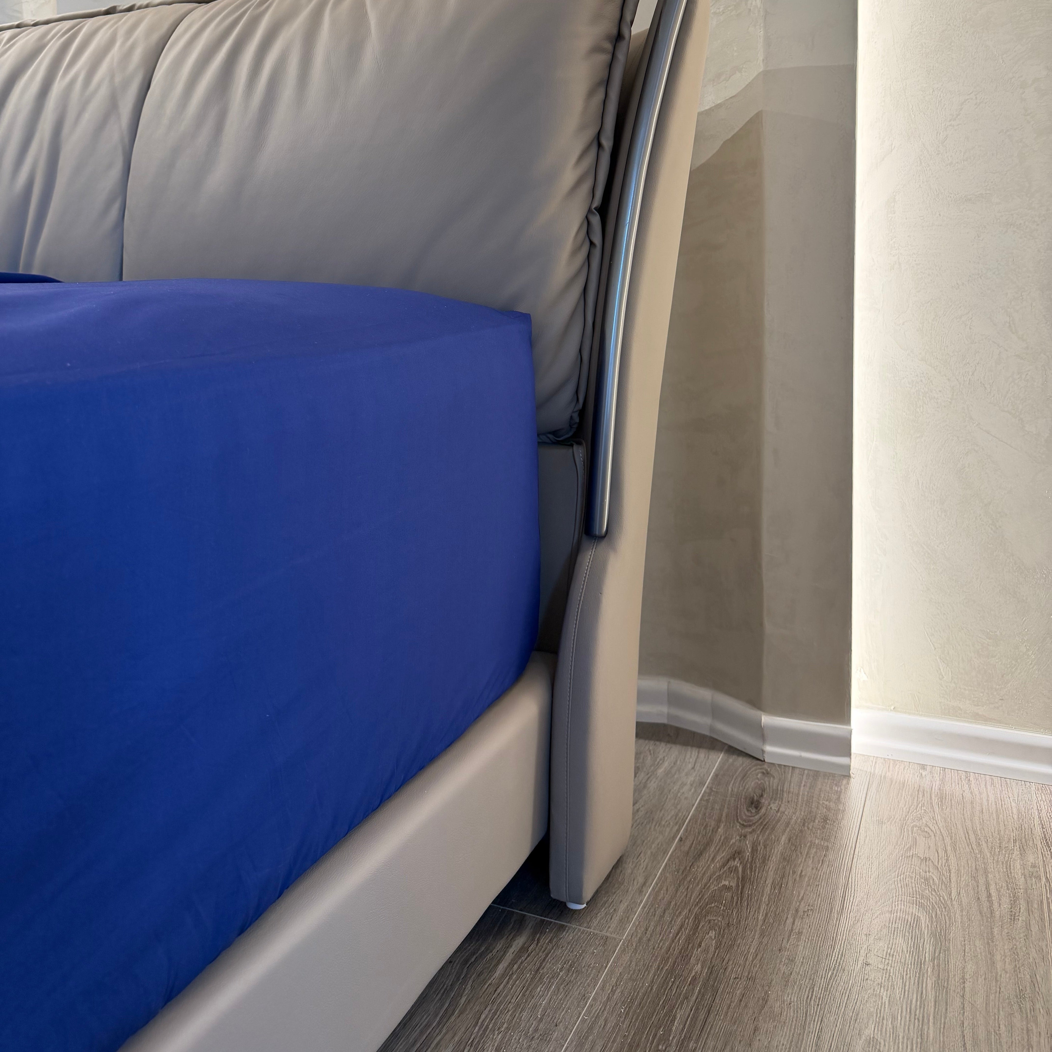 Gray cushioned chair with a blue seat cover against a neutral wall.